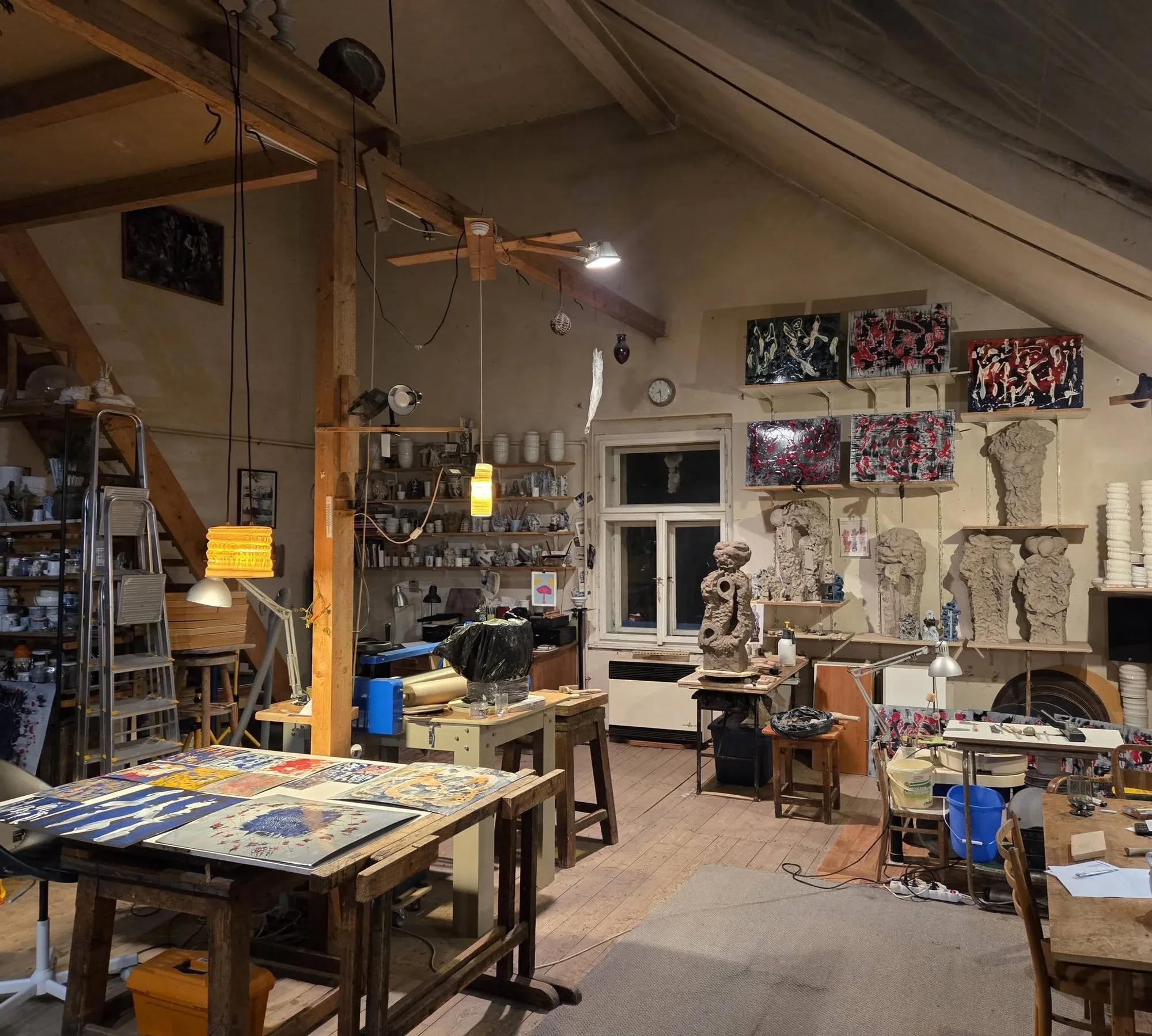 Studio with wooden beams, workbenches, shelves and sculptures in progress