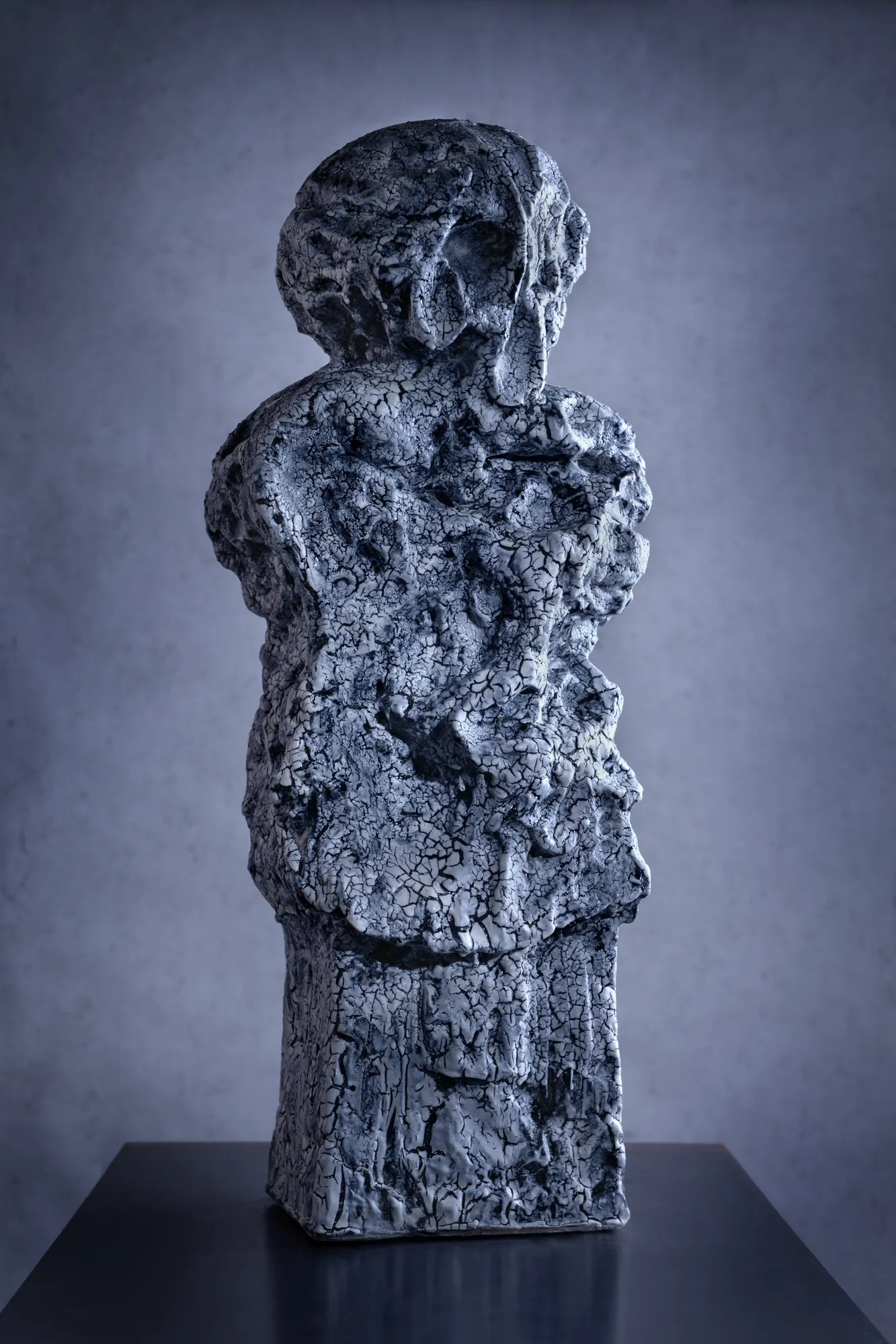 Standing figure with a crackled cobalt glaze on a prismatic base