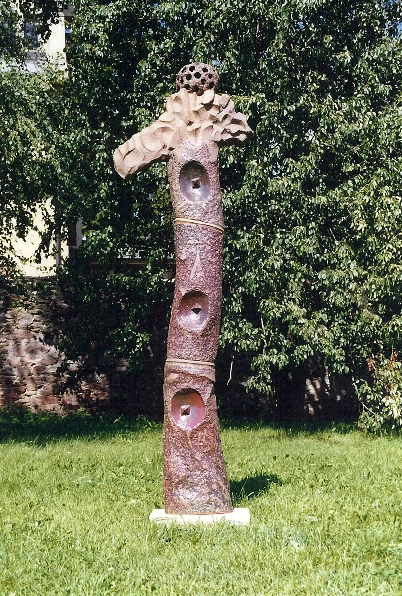 Brown figure with openings and a bird-like head in a park