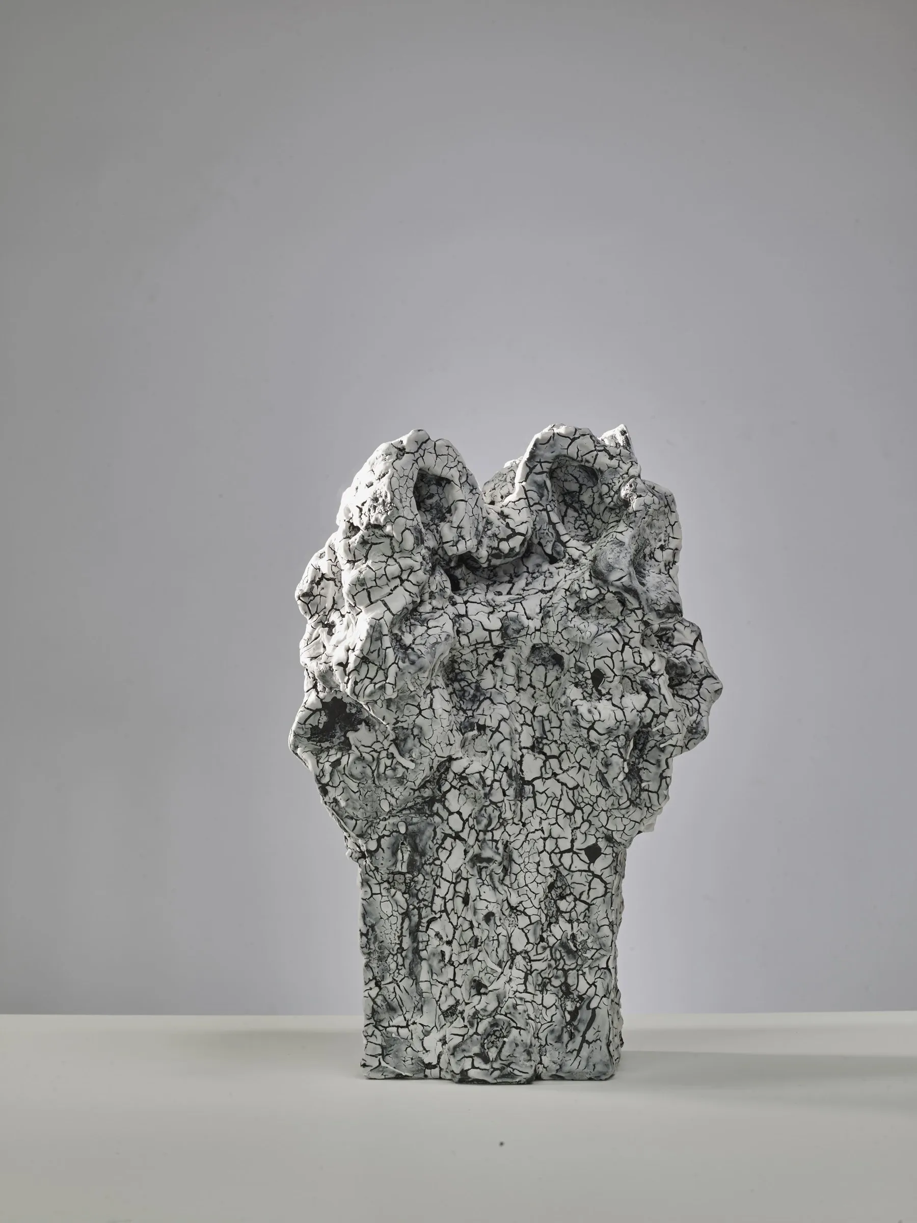 Pale porous sculpture with two peaks and a fine crackle