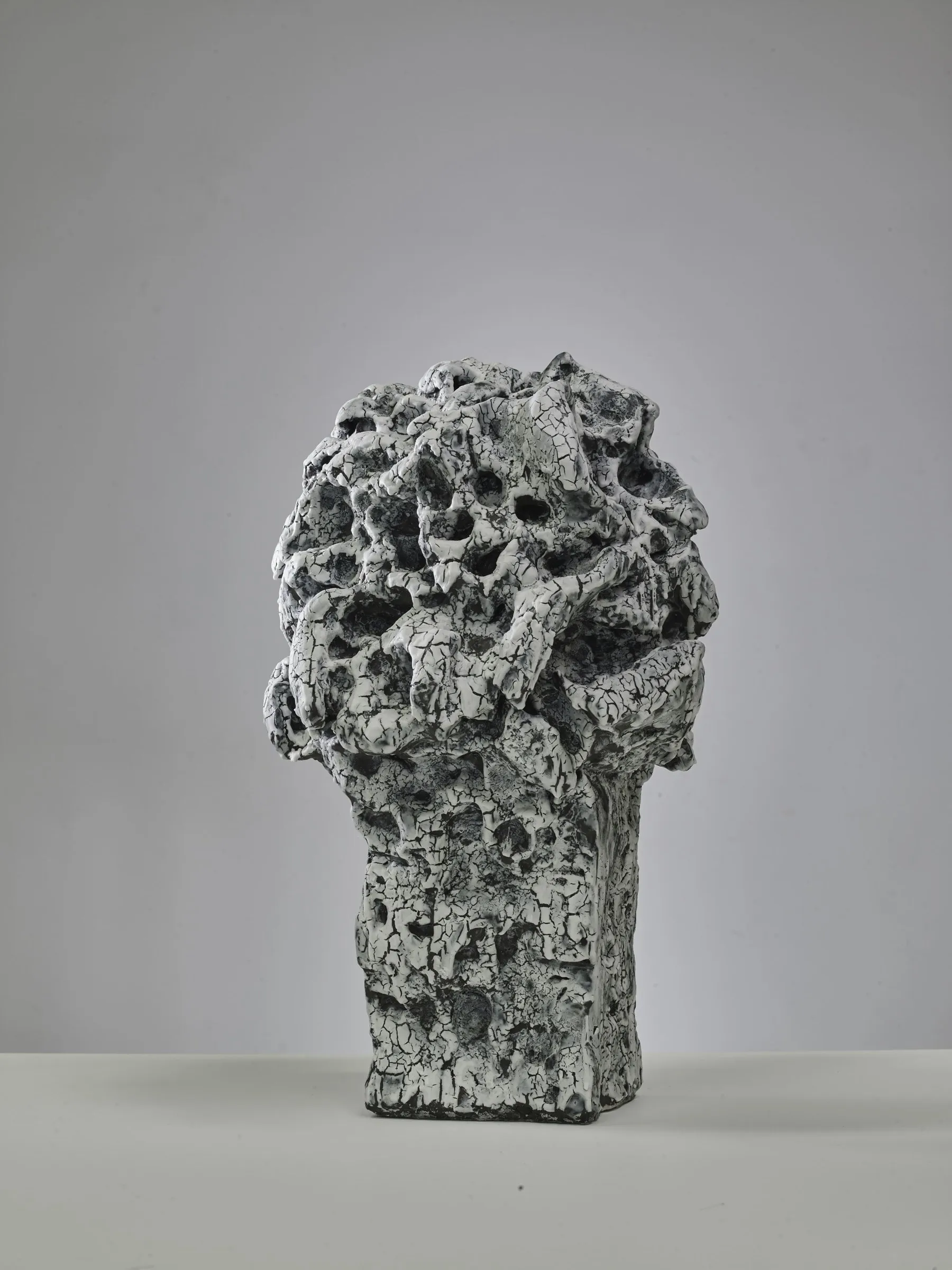 Sculpture with a spherical perforated head and dark crackle glaze