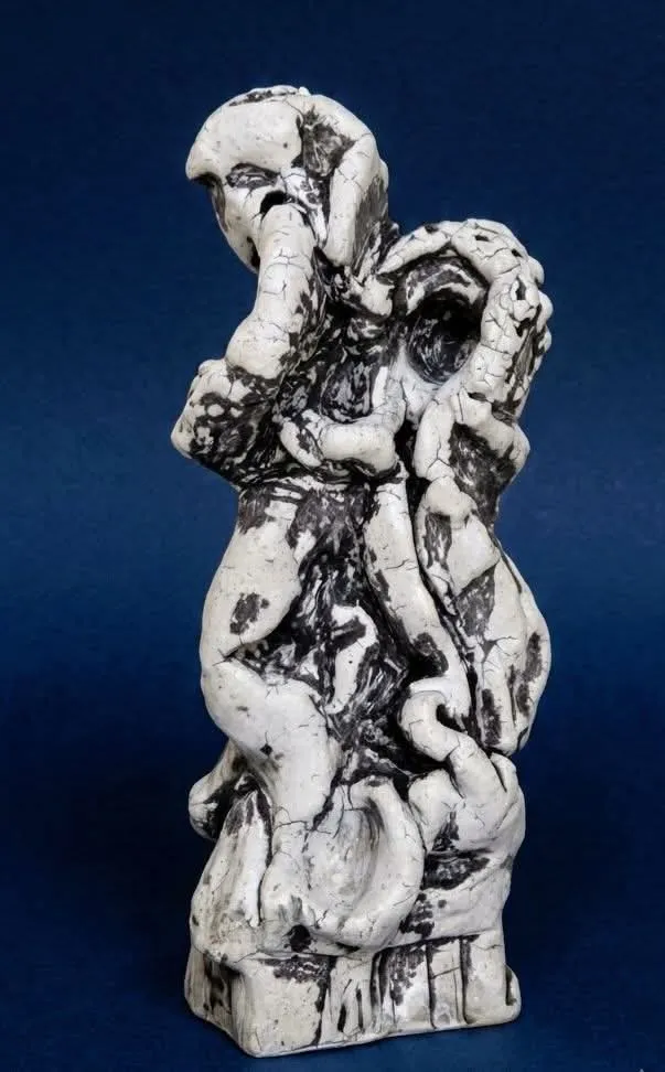 White figurative sculpture with dark patches and crackle on a blue background