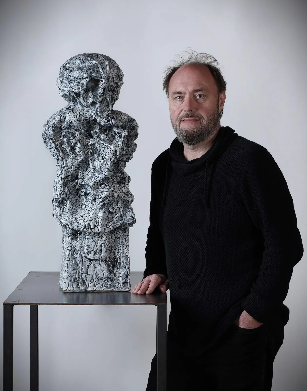 Petr Lada standing next to his sculpture with a white crackle glaze