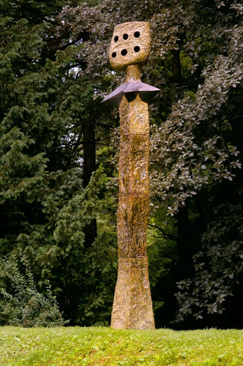 Tall slender figure with a perforated head on a lawn