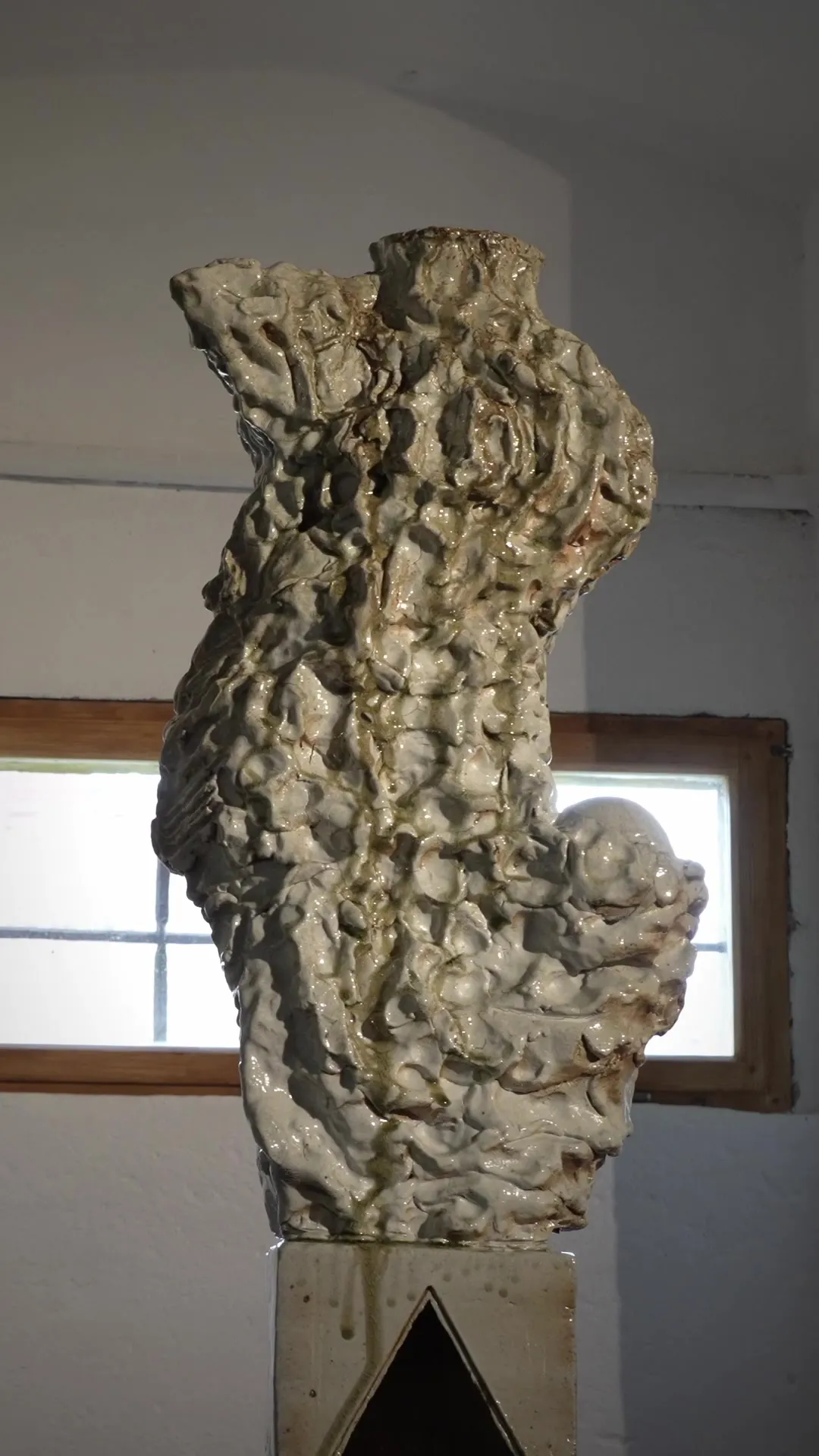 Ceramic sculpture with a crackle glaze on a plinth in the white space of the granary