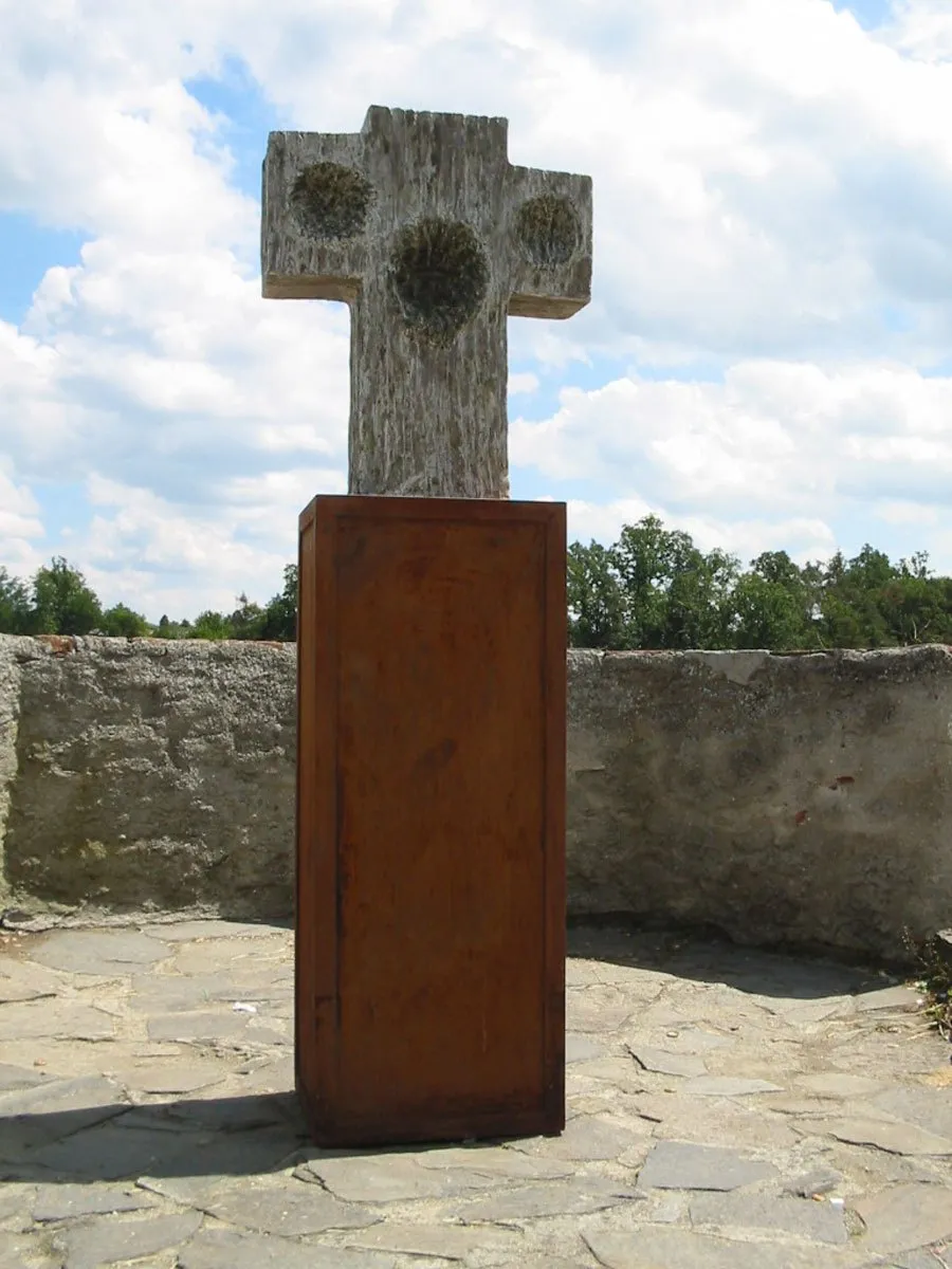 Stone cross with circular reliefs on a rusty base