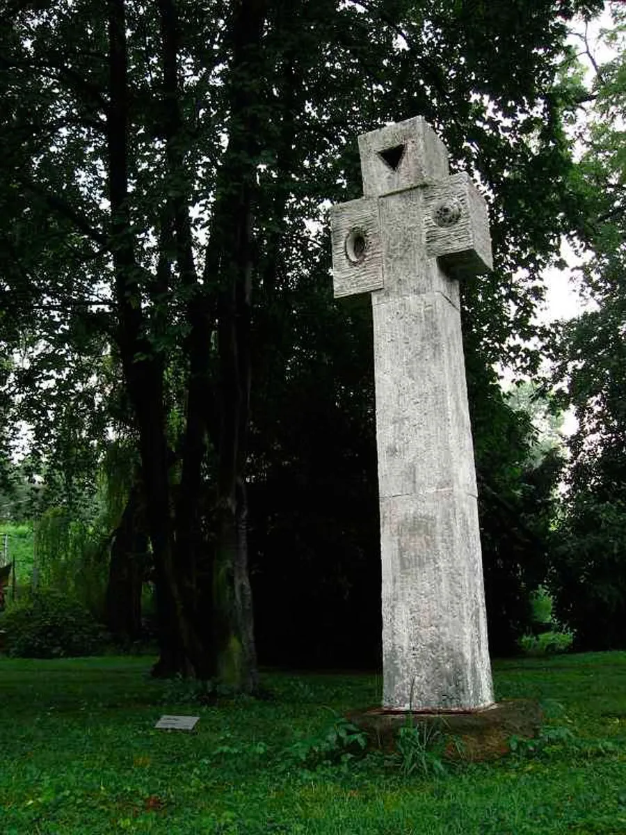 Tall pale cross with circular openings in a park