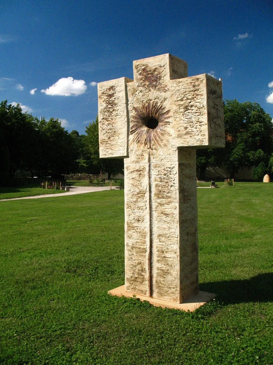 The Trinity ceramic cross on a lawn under a blue sky