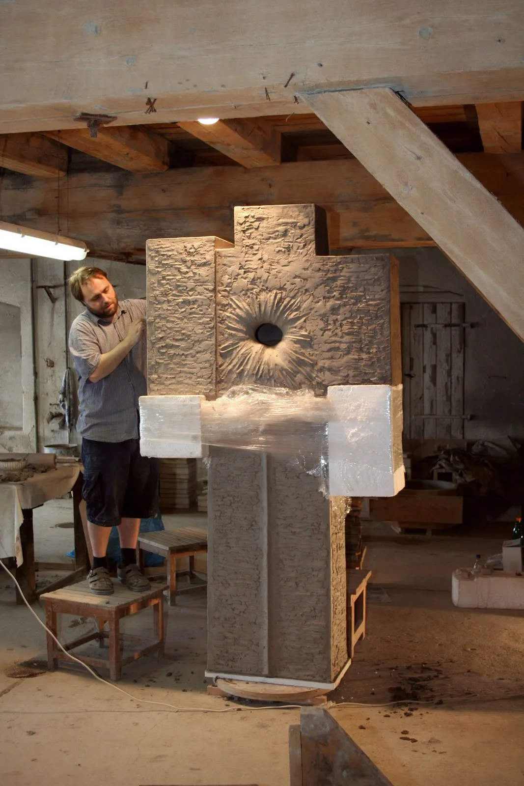 Petr Lada working on the cross in a workshop with wooden beams