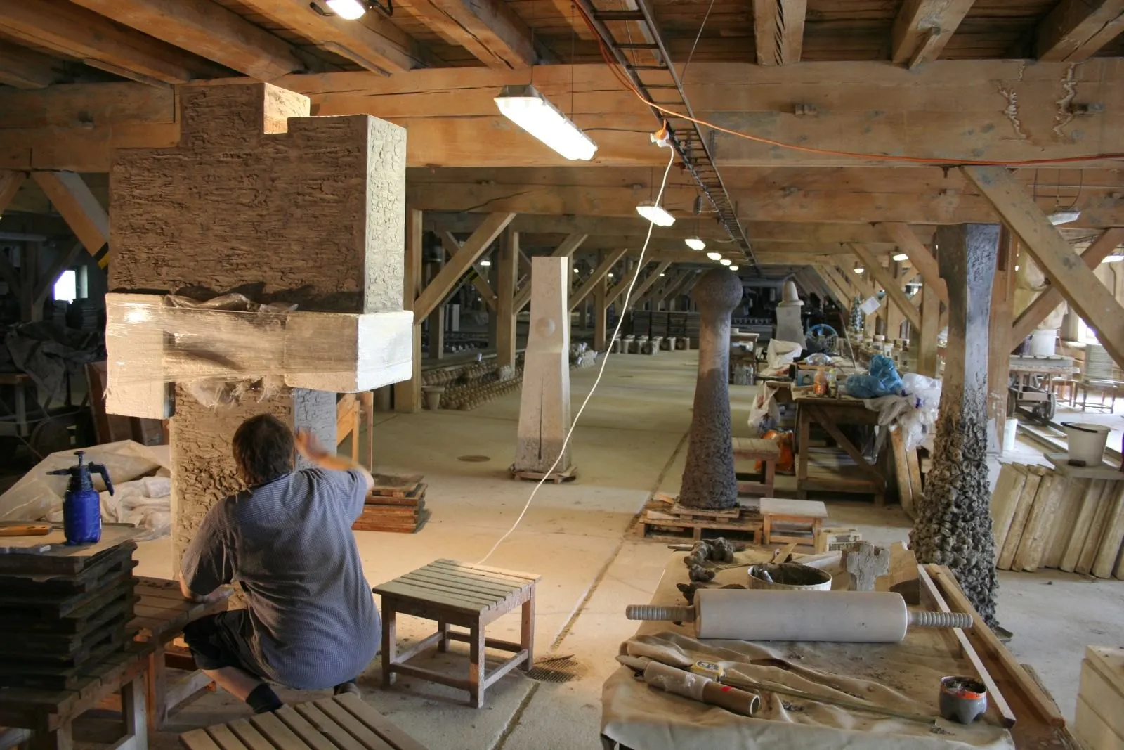 Modelling the cross in a long workshop, other sculptures in the background